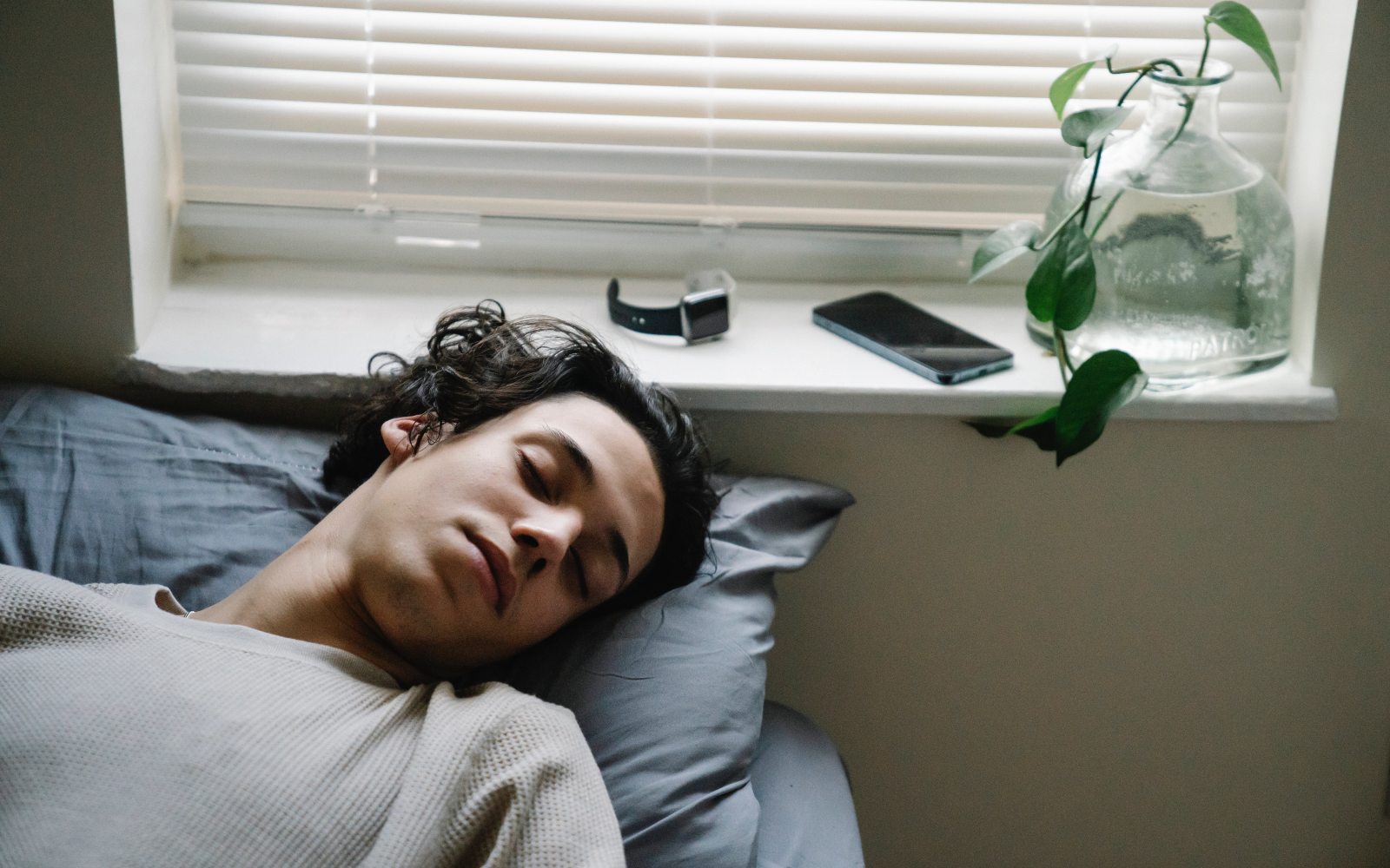 Teen asleep in day next to phone.