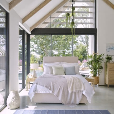 sleepeezee-divan-bed-frame-under-fully-made-bed Sleepeezee divan bed base with mattress under a fully made bed a lovely light room with glass walls.